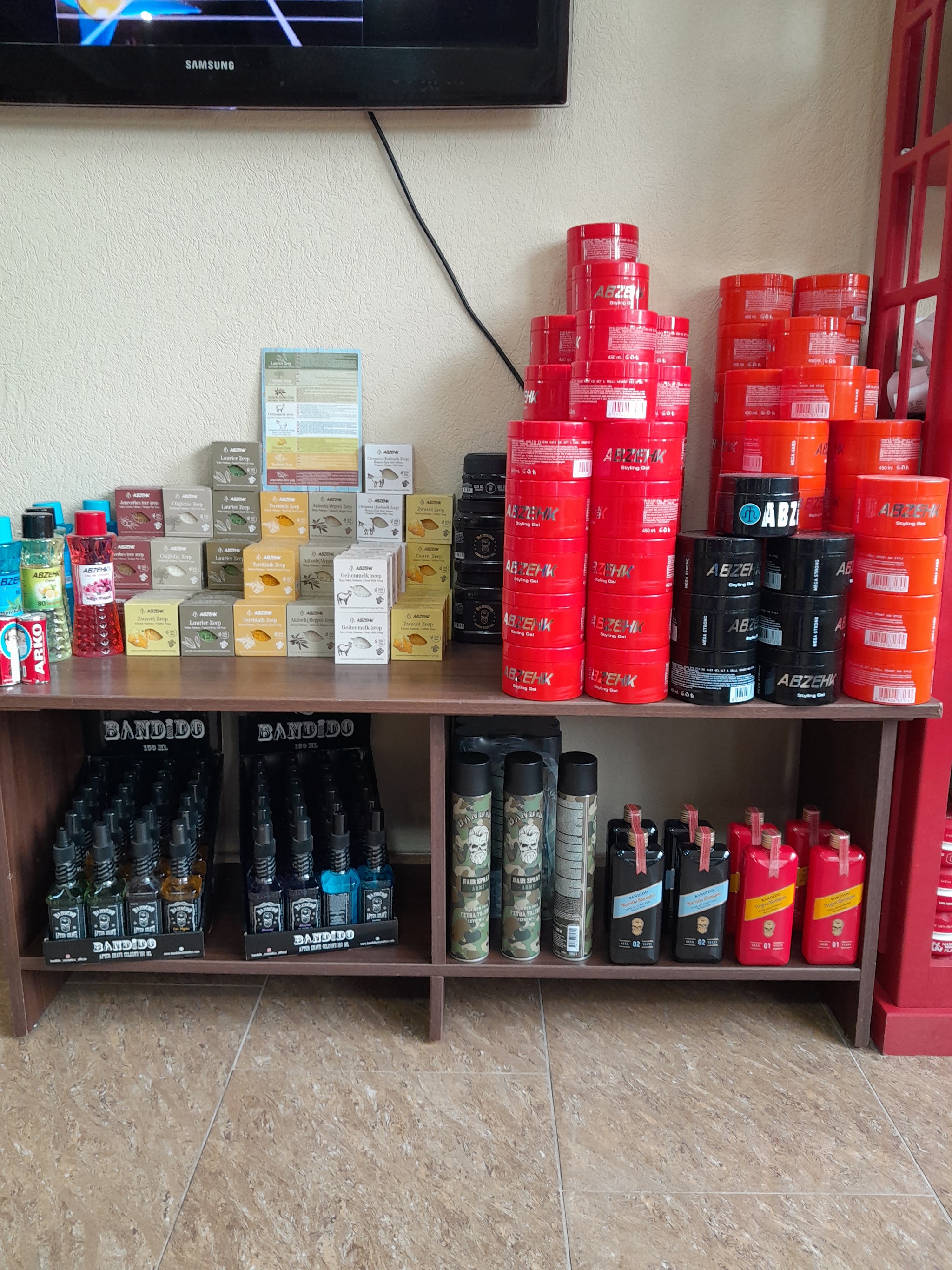 Rode potten haarwax opgestapeld op een houten tafel onder de televisie